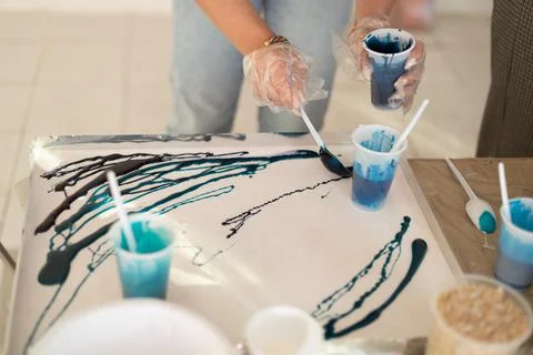 Epoxy resin different blue color in cup for abstract art. Woman hands process of Stock Photos