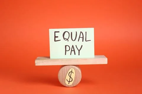 Equal pay concept. Paper note on miniature seesaw against red background Foto stock