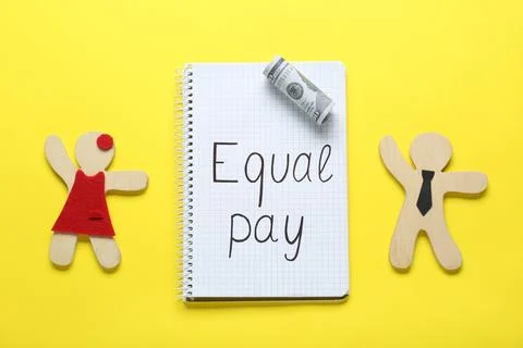 Equal pay. Open notebook, dollar banknote with wooden figures of man and wo.. Stock Photos