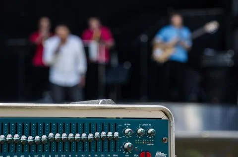An Equalizer in the Foreground with the band playing in the background Stock Photos