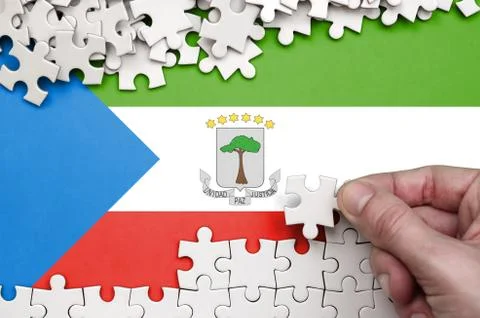Equatorial Guinea flag  is depicted on a table on which the human hand folds  Foto stock