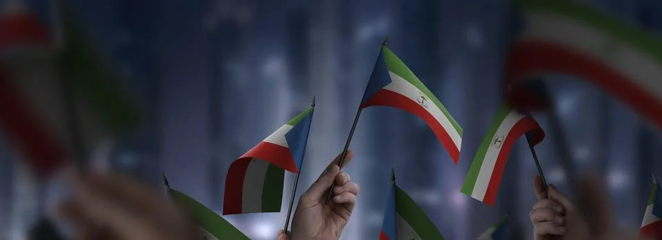 Equatorial Guinea flags in their hands on a blurred urban background Stock Photos