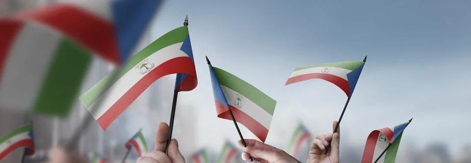 Equatorial Guinea flags in their hands on a blurred urban background Stock Photos