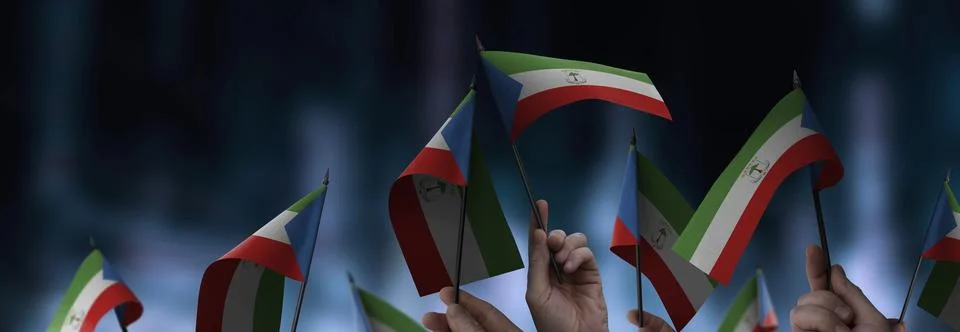 Equatorial Guinea flags in their hands on a blurred urban background Stock Photos
