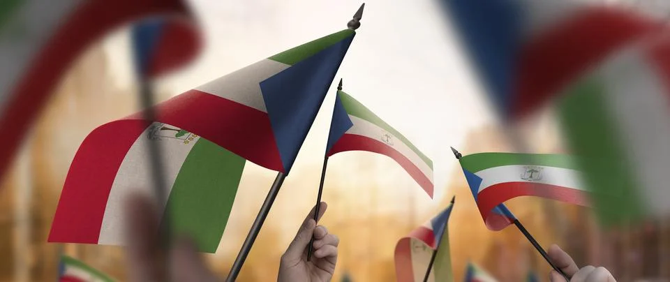Equatorial Guinea flags in their hands on a blurred urban background Stock Photos