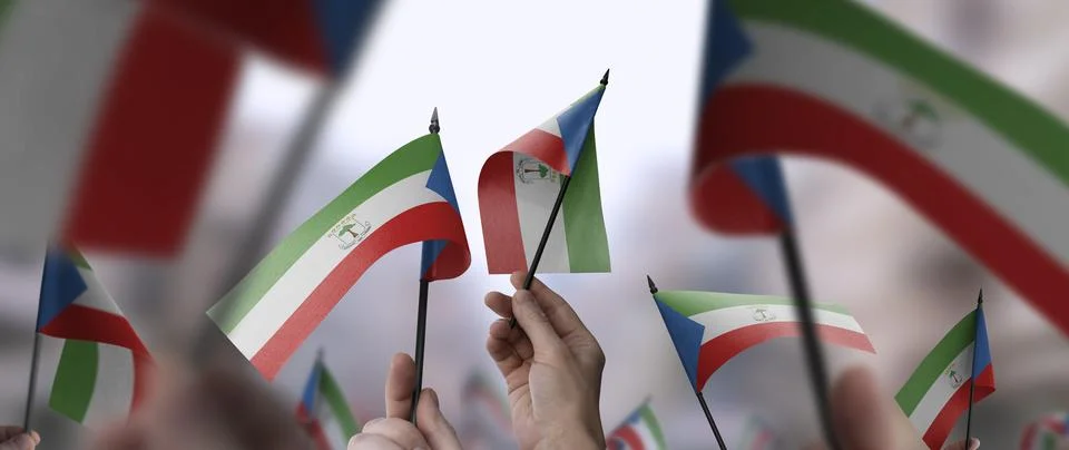 Equatorial Guinea flags in their hands on a blurred urban background Stock Photos