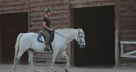 Equestrian leaving the stable riding a white horse Stock Footage 314777239