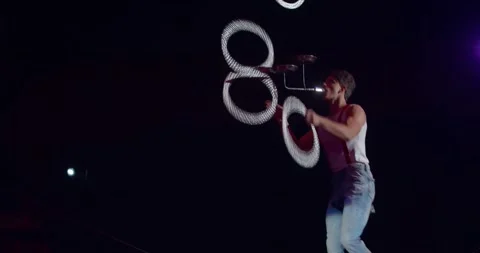 Equilibrist on a unicycle is balancing while juggling some rings, circus, 4k Stock Footage 147191248