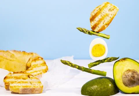 Equilibrium floating food. Fresh Bread, Asparagus, Avocado and Egg. Stock Photos