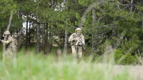 Equipped soldiers moving through forest with rifle ready to shoot. Stock Footage 127648528