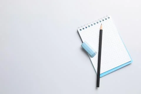 Eraser, pencil and notepad on light background, top view. Space for text Stock Photos