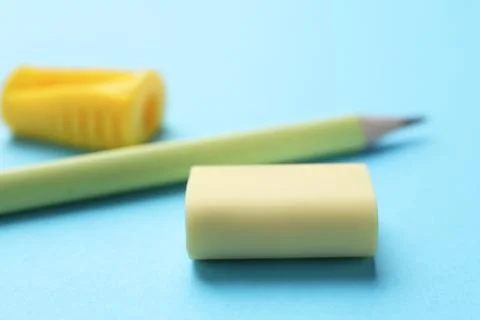 Eraser, pencil and sharpener on light blue background, selective focus Stock Photos