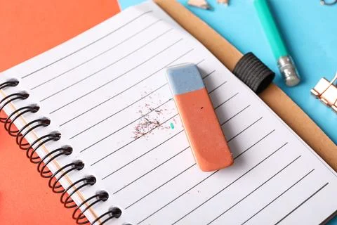 Erasers with notebook on color background Stock Photos
