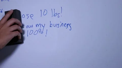 Erasing goals written on a dry erase board and writing a new goal Stock Footage 42237219