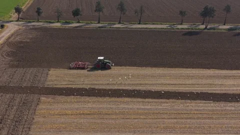 Erial view of eco-friendly farming with a tractor cultivating land. Focus on Stockbeeldmateriaal 332815463