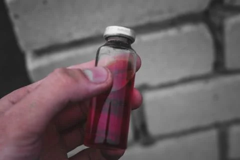 Erlenmeyer flask with red solution standing on a stone surface. Stock Photos