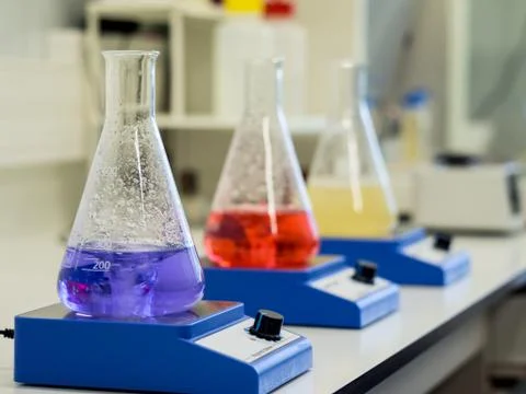 Erlenmeyer flasks with colorful solutions on a magnetic stirrer in a lab Stock Photos