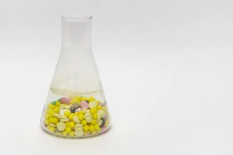 Erlenmeyer flasks, filled with tablets and dragee. On white background 库存照片
