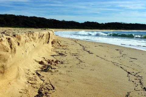 Eroded beach sand after a storm background Stock Photos