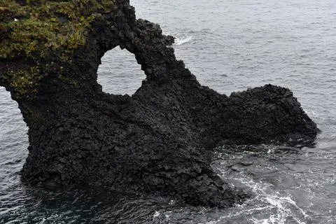 Eroded circular opening in the basalt rock of Gatklettur at Arnarstapi, Icela Stock Photos