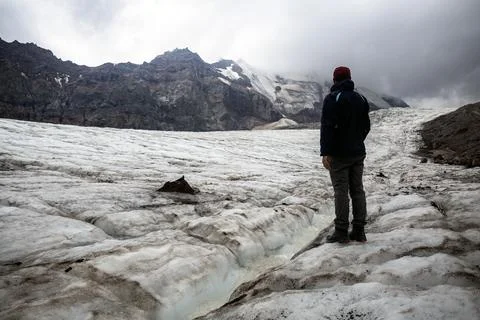 Eroded Elegance of mount Kazbegi: A trekker stands on a snowy slope, mounta.. Stock Photos