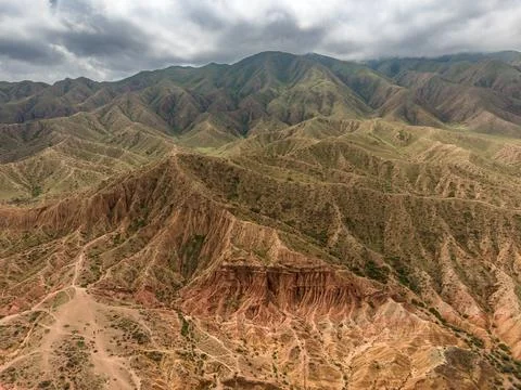Eroded mountain ridges stretch beneath storm clouds across Kyrgyzstan wilde.. Stock Photos
