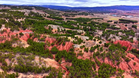 Eroded red earth landscape with pine trees and road Video stock 330492377