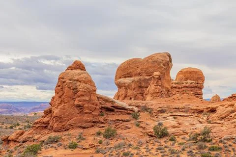 Eroded red rock formations stand against cloudy desert skies. 写真素材