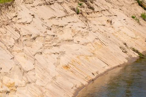 Eroded riverbank with sandy cliffs and water flow Stock Photos