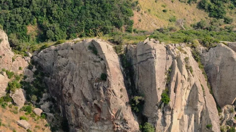 Eroded sandstone cliff face with shrubs on a green hillside Stock Footage 345088732