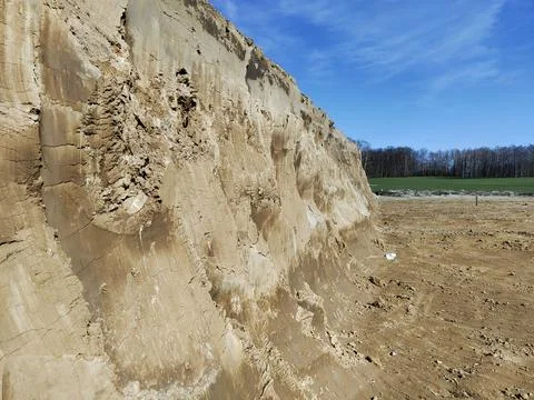 Eroded sandstone cliff in open field under clear blue sky Stock Photos