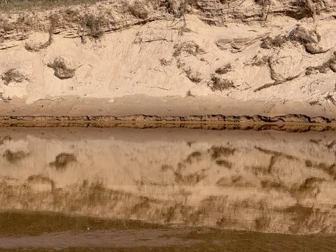 Eroded Sandy Riverbank Reflection in Calm Water Landscape Stock-Fotos