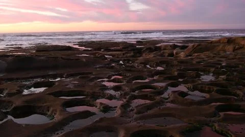 Eroded tide pool rock formation in California. Sunset sky reflection in water. Stock Photos