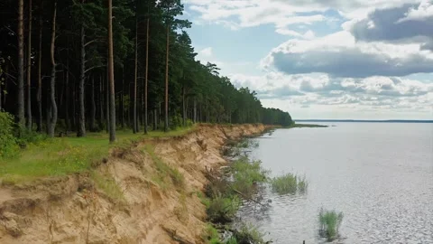 Eroding Cliffs, Cascading Pines, Waves Embrace Sandy Shores Under Cumulus Ballet Stock Footage 257781775