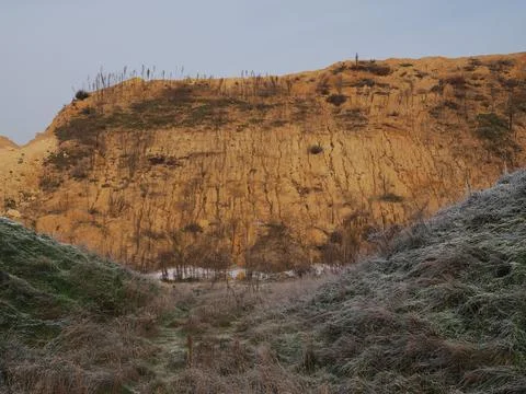 Eroding mountain and a valley with frozen grass under the blue sky 스톡 사진