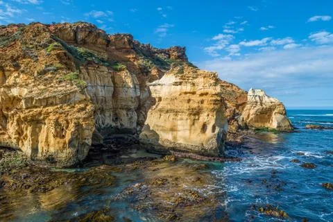 Eroding rocks at ocean coastline on bright sunny day Stock Photos