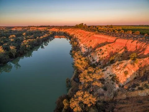 Eroding sandstone cliffs over Murray River at glowing orange sunset. Foto stock