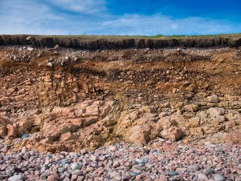 Eroding soil, subsoil and bedrock at a pebble beach near Sand Wick Stock Photos