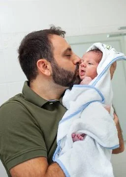 Erstes Bad eines neugeborenen Jungen. Das Baby liegt im Bademantel in den ... Stock Photos