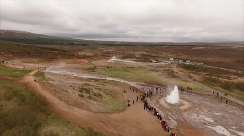 Erupting hot spring and crowded footpaths on a steaming field Видео 64895394