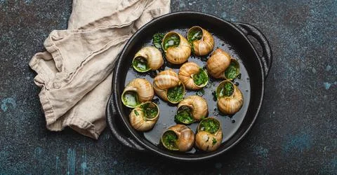 Escargots de Bourgogne Cooked Snails with Garlic Butter and Parsley in black Stock Photos