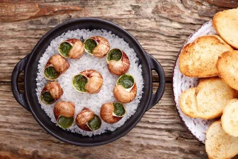 Escargots de Bourgogne - Snails with herbs butter on wooden background. Salad Stock Photos