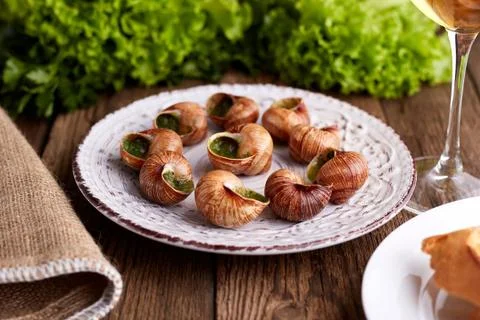 Escargots de Bourgogne - Snails with herbs butter on wooden background. Salad Stock Photos