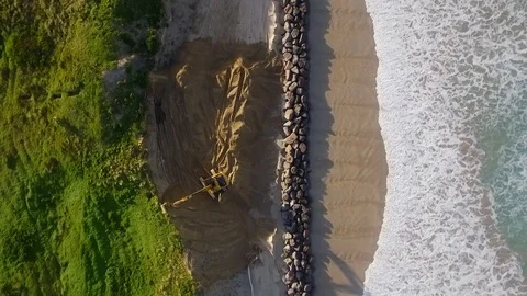 Escavator helping save a beach from sea erosion Stock Footage 87859783