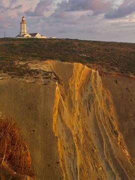 Espichel cape lighthouse sitting on top of a cliff during sunset. Sesimbra,.. Stock Photos