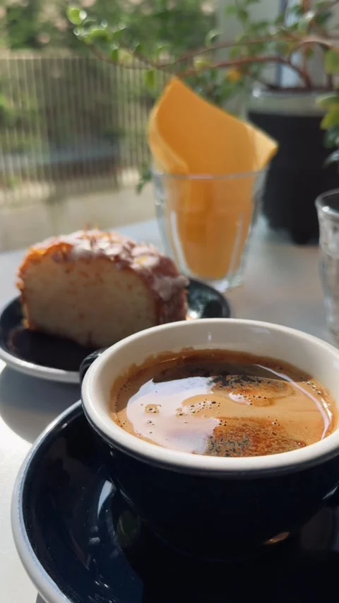 Espresso and slice of glazed lemon cake in sunny modern café interior Stock Footage 310676972