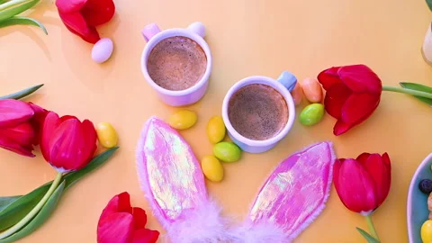 Espresso coffee in bright cups, Easter chocolate eggs, pink bunny ears Video stock 146872189