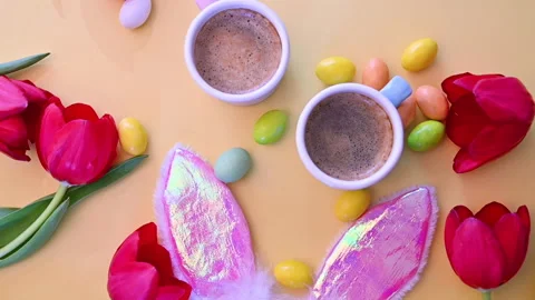 Espresso coffee in bright cups, Easter chocolate eggs, pink rabbit ears and red Stock Footage 146872341