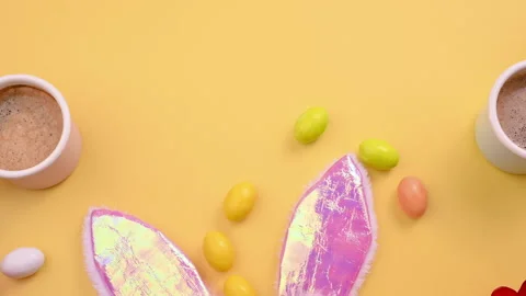 Espresso coffee in bright cups, Easter chocolate eggs, pink bunny ears and red Video stock 146885090