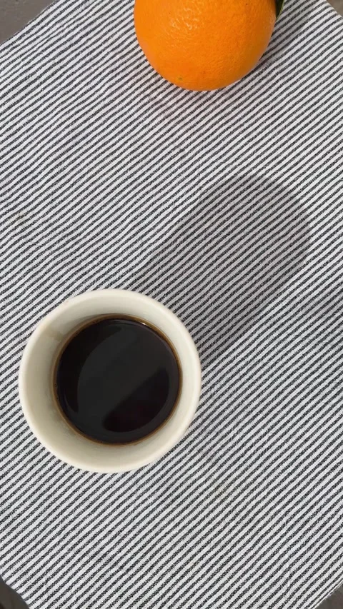 Espresso cup and orange on striped linen cloth, flat lay Stock Footage 344412220